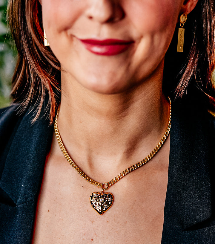 a model wearing a big gold heart necklace