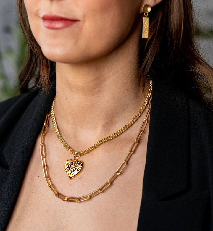 a model wearing a big gold heart necklace