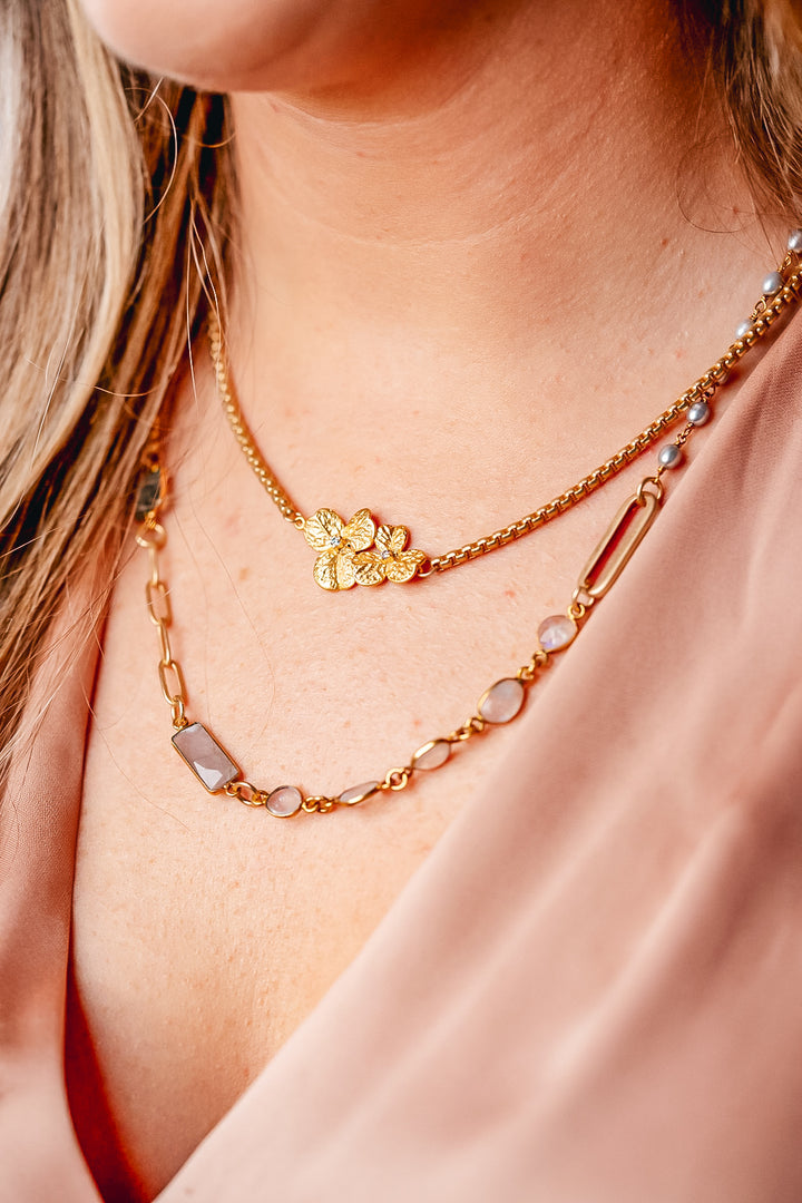 a modal wearing a mixed gemstone necklace with gray and rainbow moonstone, aquamarine and rice pearls.