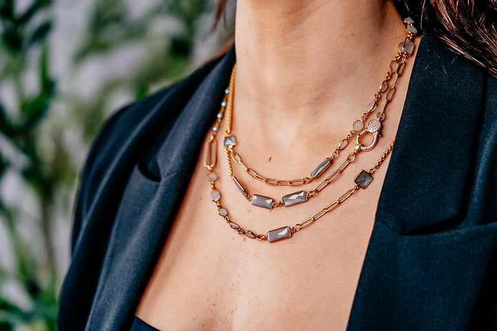 a modal wearing a mixed gemstone necklace with gray and rainbow moonstone, aquamarine and rice pearls.