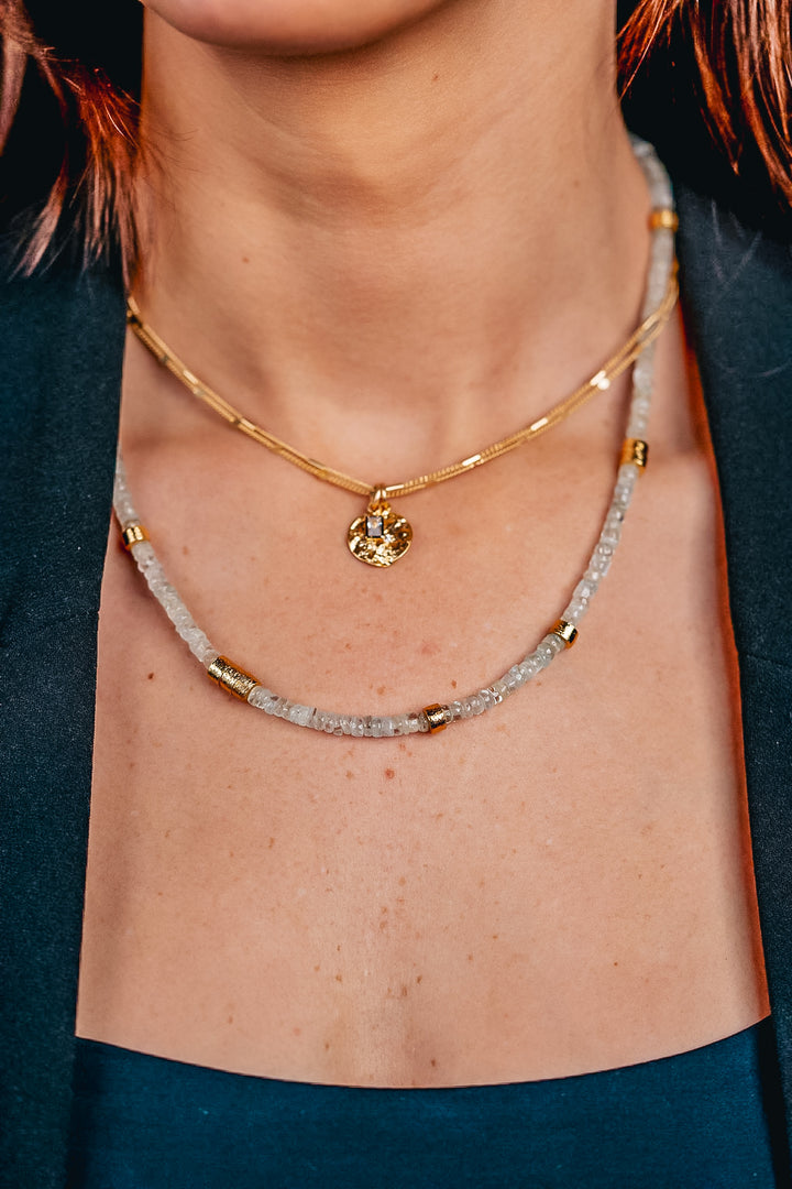 a model wearing a gold aquamarine bead necklace with gold accents.