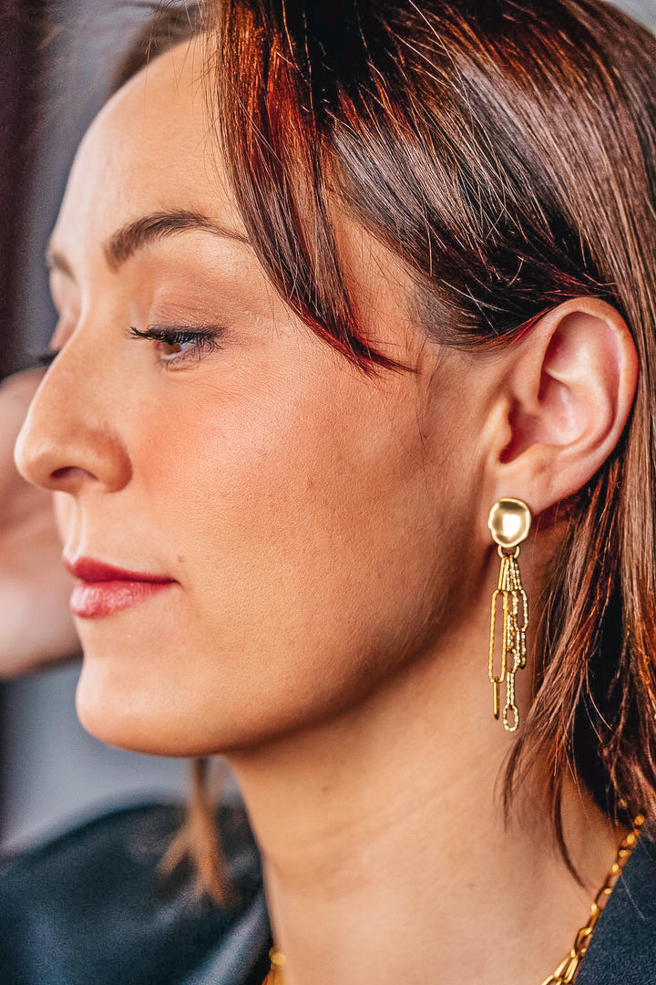 A model wearing a gold paperclip chain earring