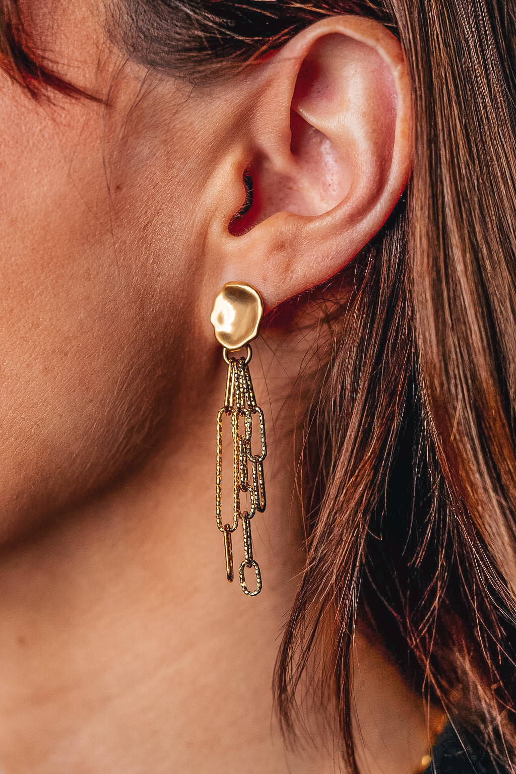 A model wearing a gold paperclip chain earring