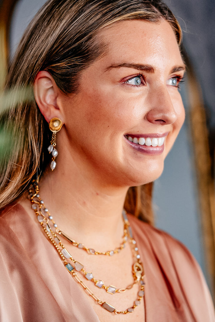 a modal wearing a mixed gemstone necklace with gray and rainbow moonstone, aquamarine and rice pearls.