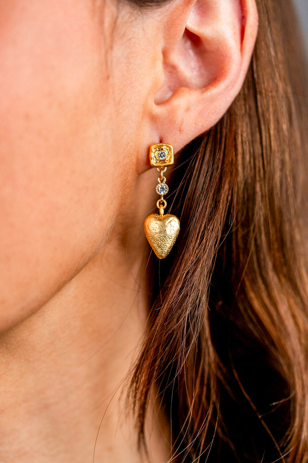 A model wearing gold heart dangle earrings