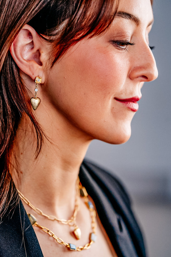 A model wearing gold heart dangle earrings