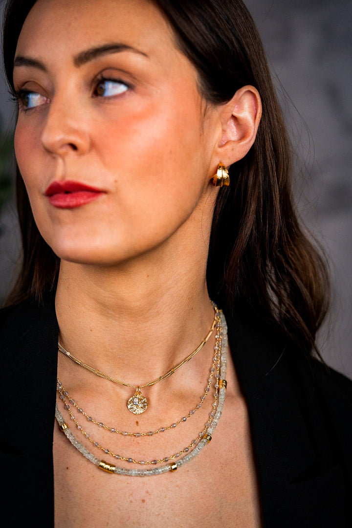 a model wearing a gold hammered coin necklace