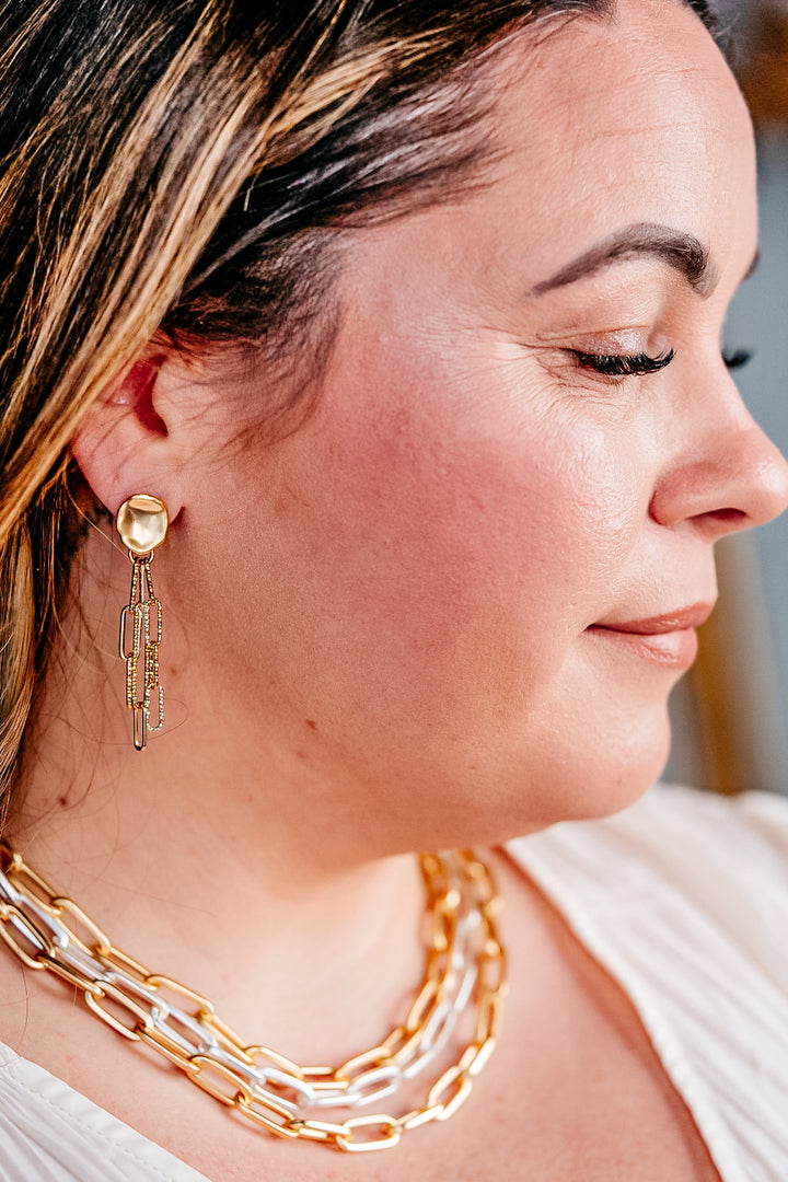 A model wearing a silver and gold paperclip chain earring