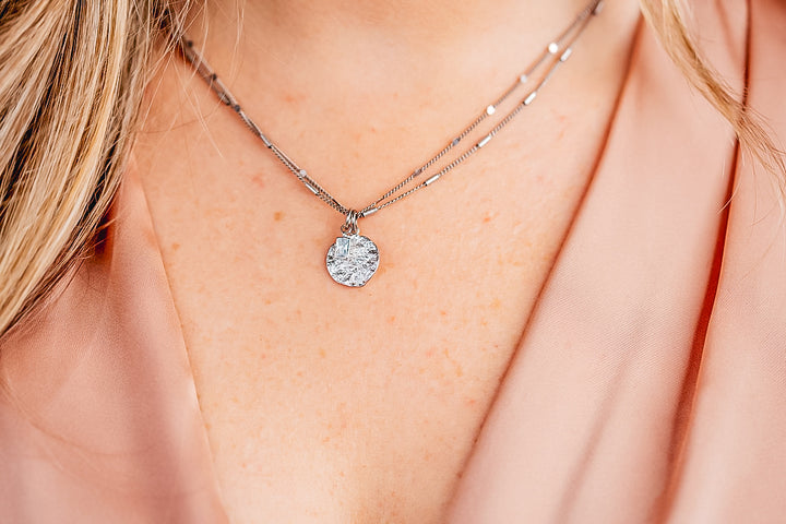 a model wearing a silver hammered coin necklace