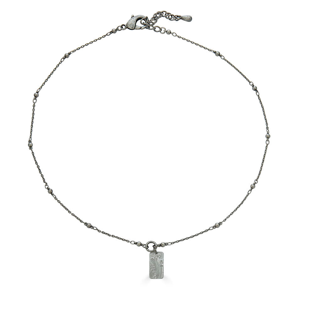 a silver rectangle flower necklace on a delicate chain