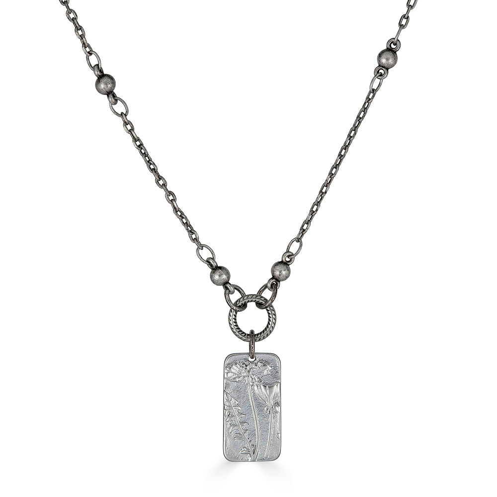 a silver rectangle flower necklace on a delicate chain