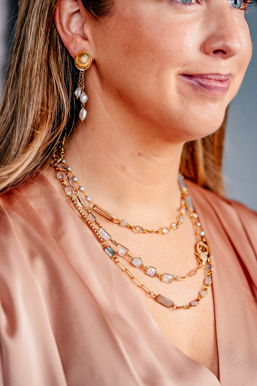 a modal wearing a mixed gemstone necklace with gray and rainbow moonstone, aquamarine and rice pearls.